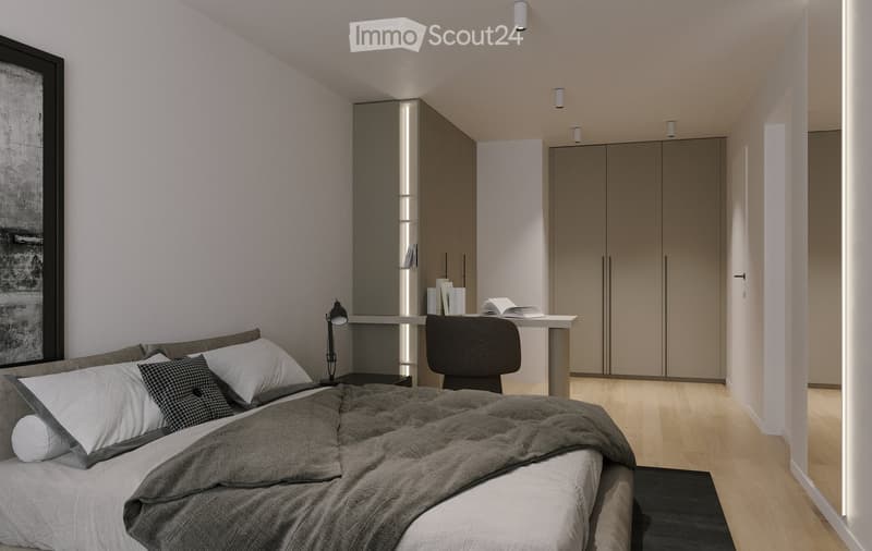 Modern bedroom with a large bed, pillows, and a blanket, a sleek wardrobe, a desk with a chair, and a lamp. The room features light wooden flooring and built-in storage.