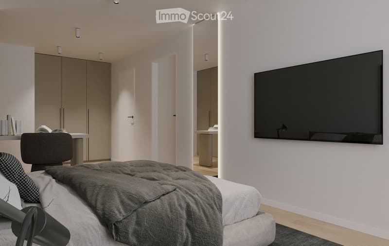 Modern bedroom with a large bed, a wall-mounted screen, a chair, a small table with books, and a wardrobe in the background.