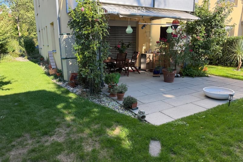 Well-maintained garden with a paved patio, outdoor dining set, potted plants, and a small water feature.