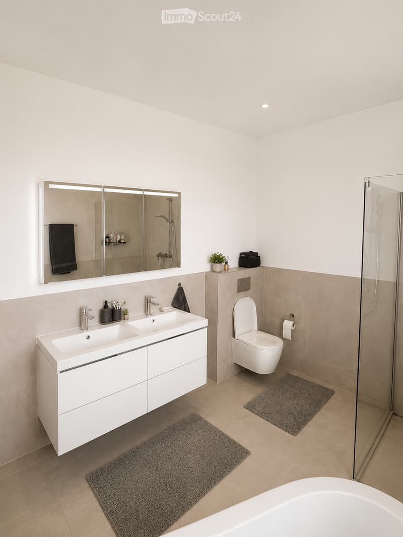 Modern bathroom with a double sink, large mirror, toilet, and glass-enclosed shower. Beige tiles and white cabinetry.