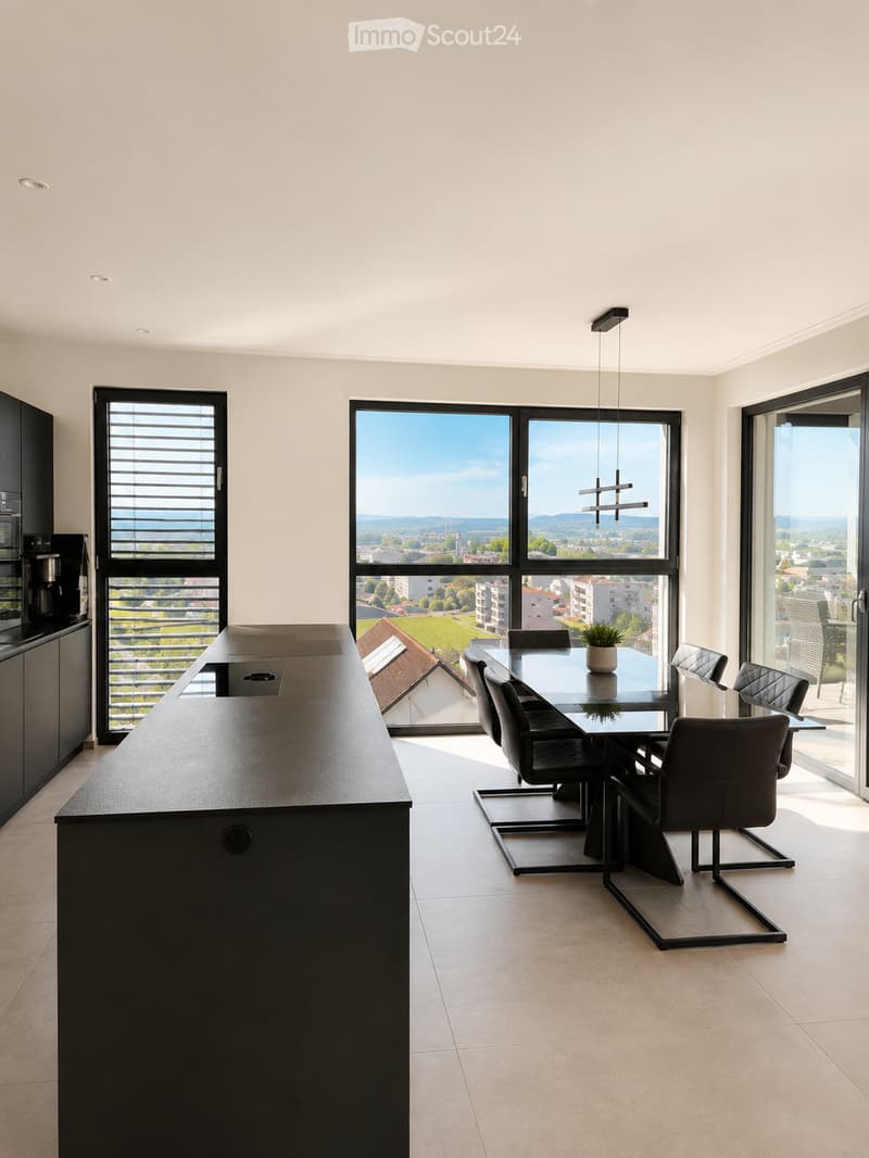 Modern kitchen and dining area with large windows, black kitchen island, glass dining table, black chairs, and a small potted plant.