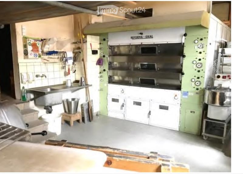Commercial kitchen with stainless steel oven, sink, cabinets, and various appliances.