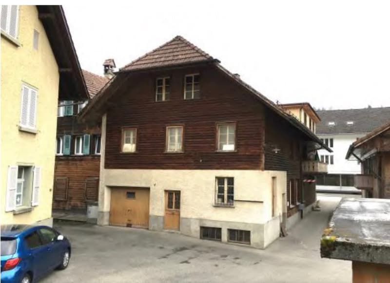 A multi-story wooden building with a traditional design, featuring multiple windows and a garage entrance.