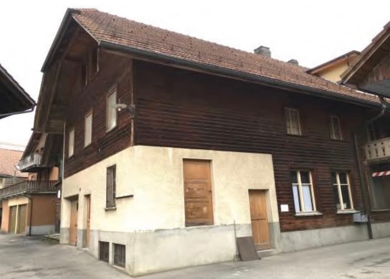 A multi-story wooden building with a tiled roof, multiple windows, and a mix of wooden and plaster facades.