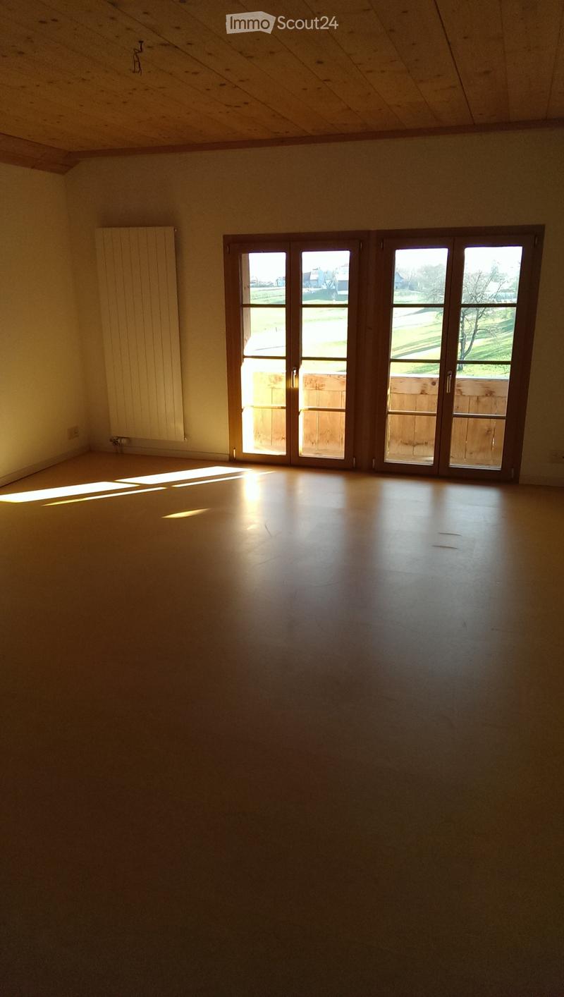 Empty room with wooden floor, large windows, and natural light. No furniture or equipment present.