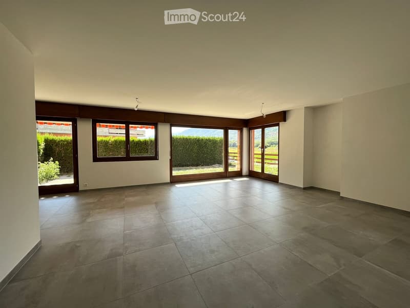 Empty room with tiled floor, large windows, and sliding glass doors leading to an outdoor area.