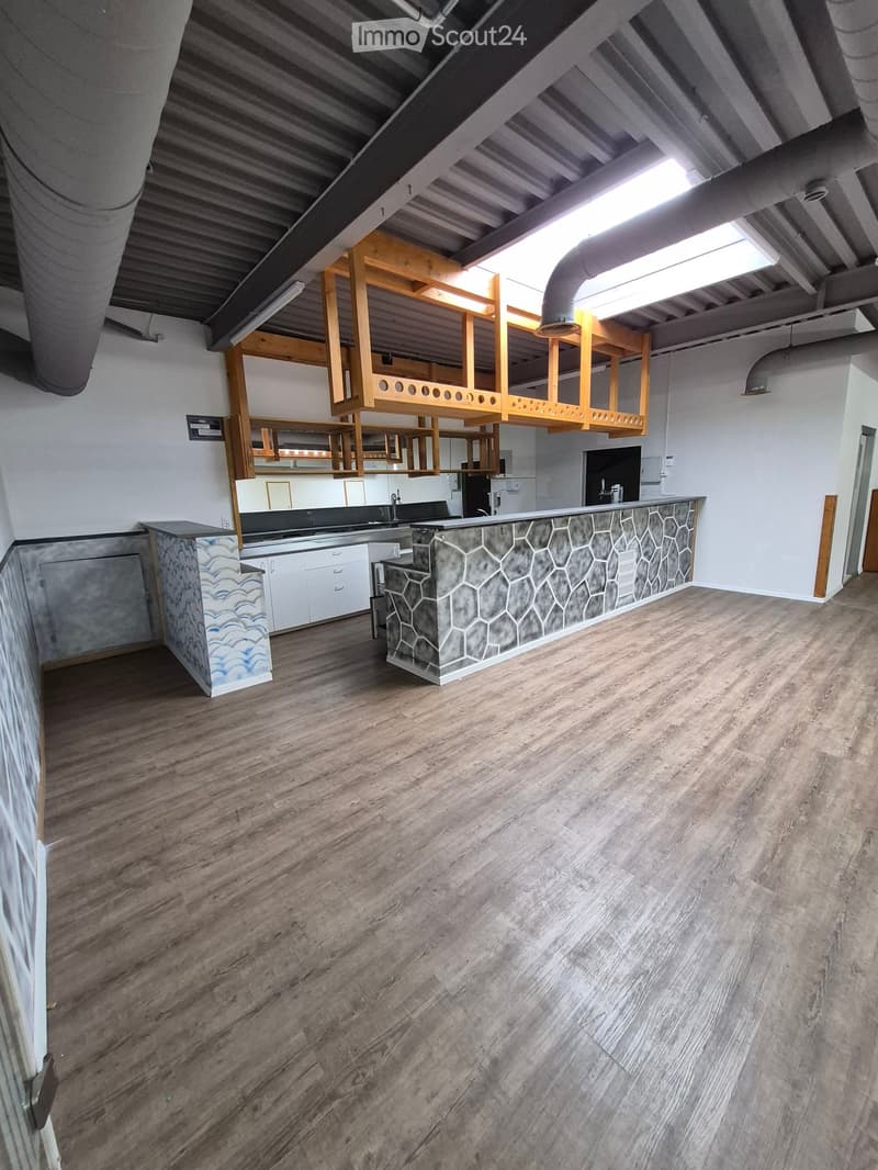 Modern kitchen with wooden flooring, white cabinets, a central island with a stone countertop, and built-in shelving units.