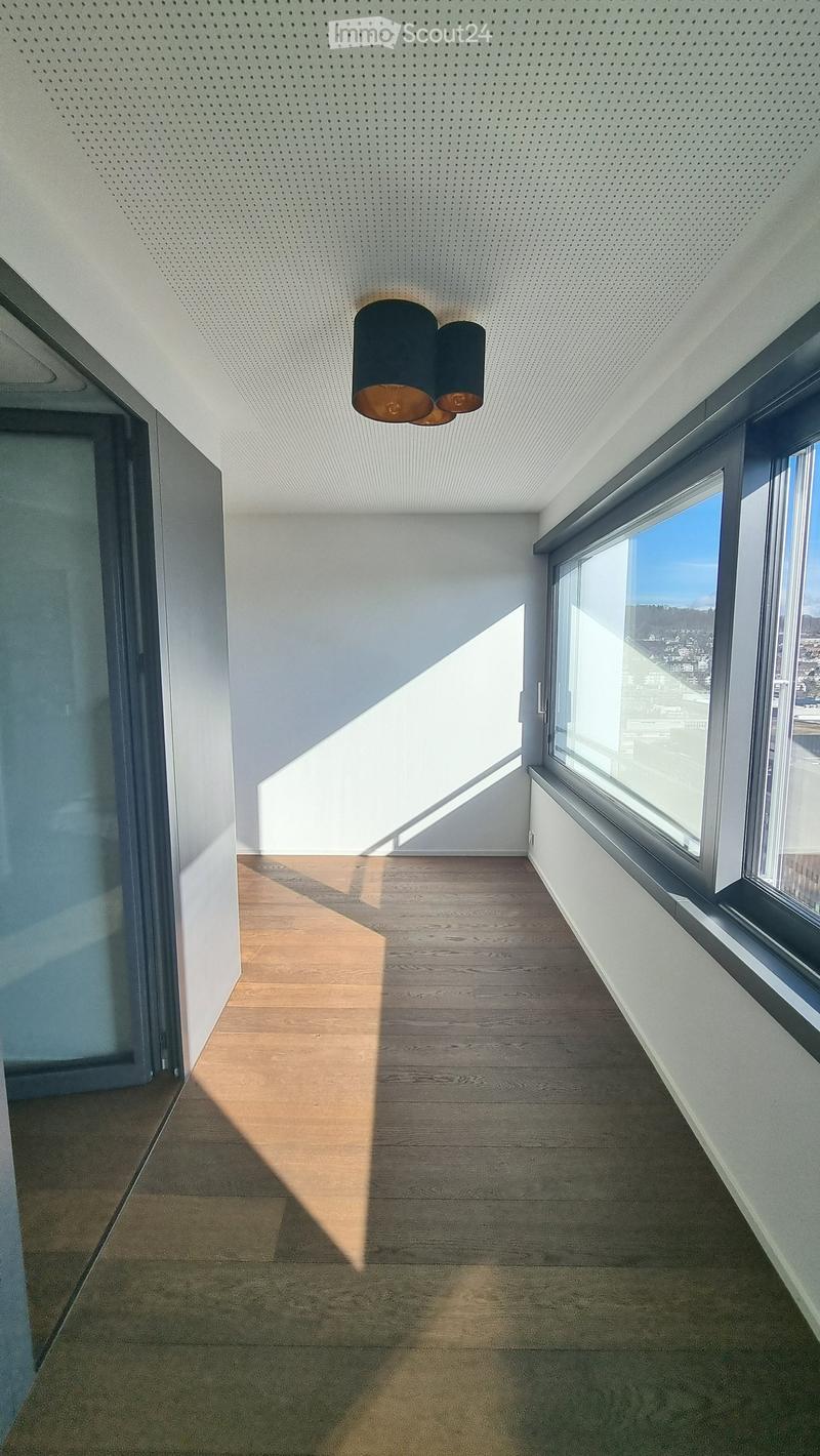 Empty room with wooden floor, large windows, and a ceiling lamp