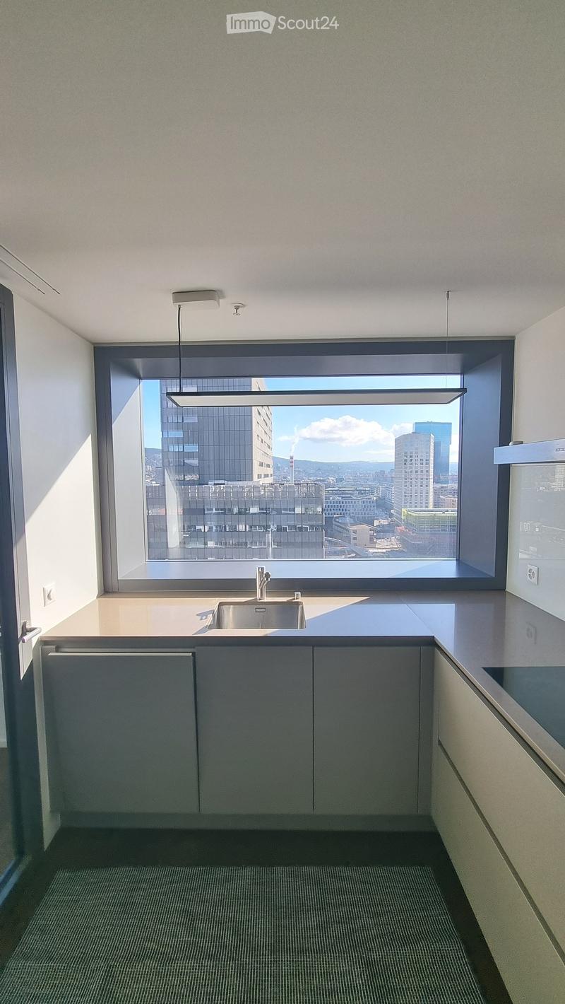 modern kitchen with large window, stainless steel sink, modern cabinets, countertop, and a view of the city