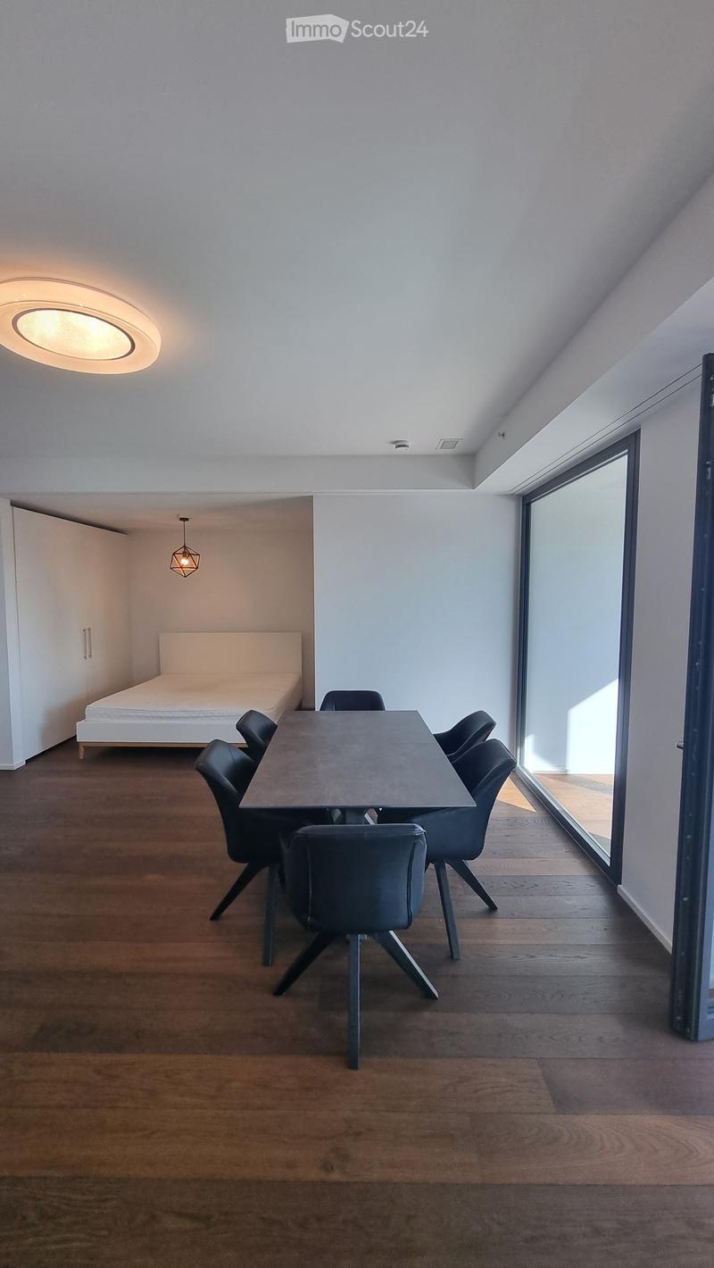 Dining room with a table and chairs, a bed, and a glass door leading to a balcony