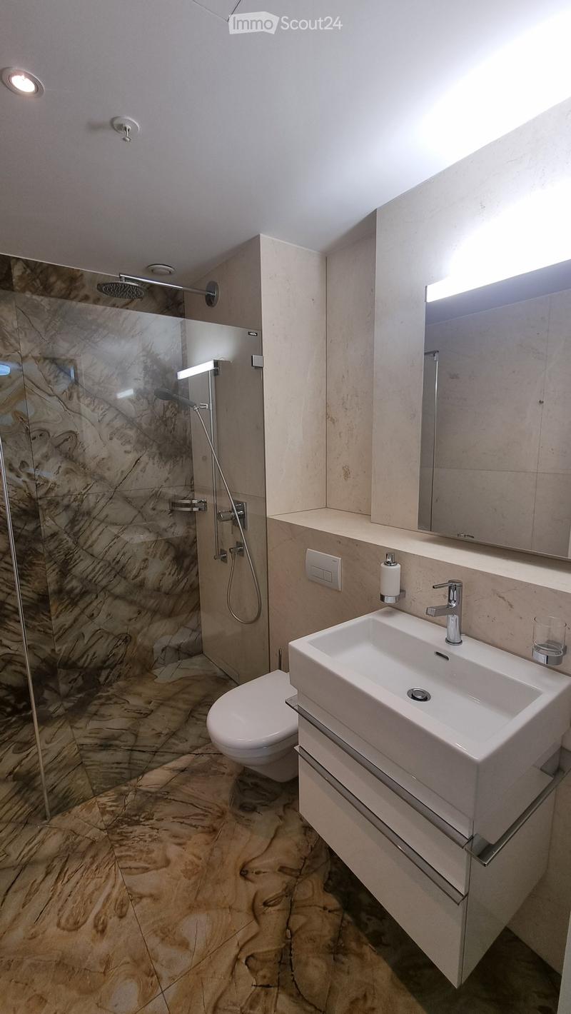 Bathroom with shower, toilet, sink, mirror, and marble flooring