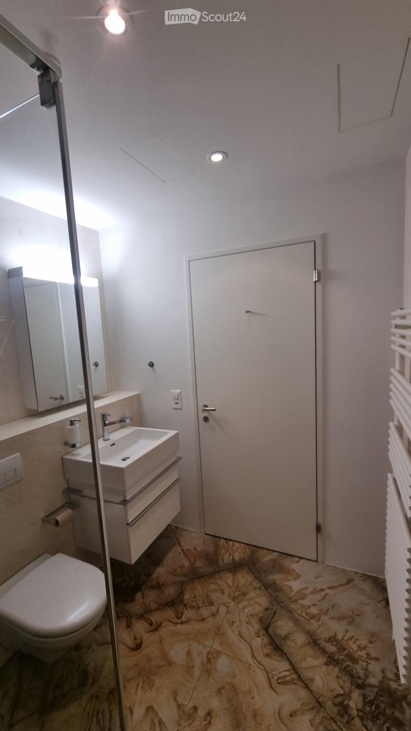 Bathroom with white sink, mirror, toilet, and marble flooring