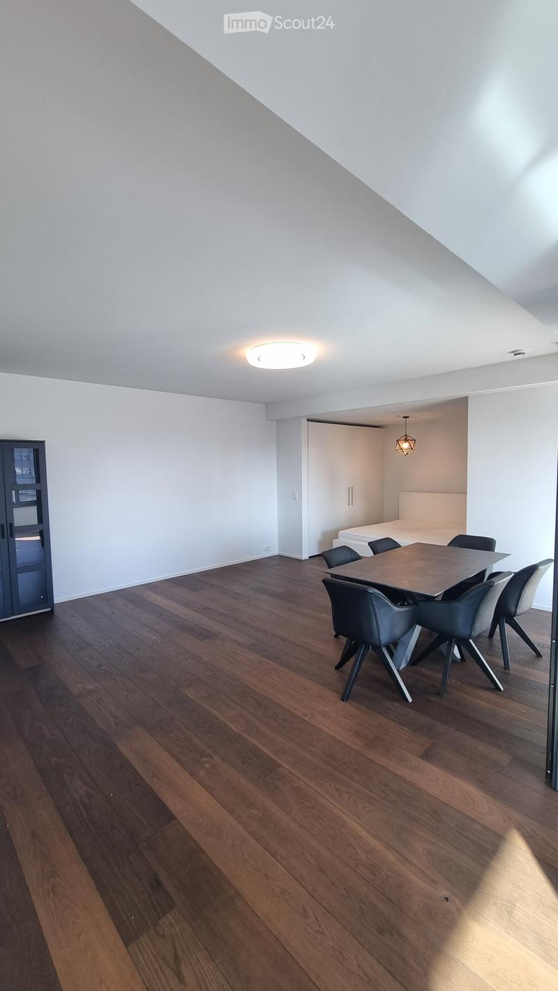 Dining room with wooden floor, white walls, modern ceiling light, dining table, chairs, and a small white cabinet.