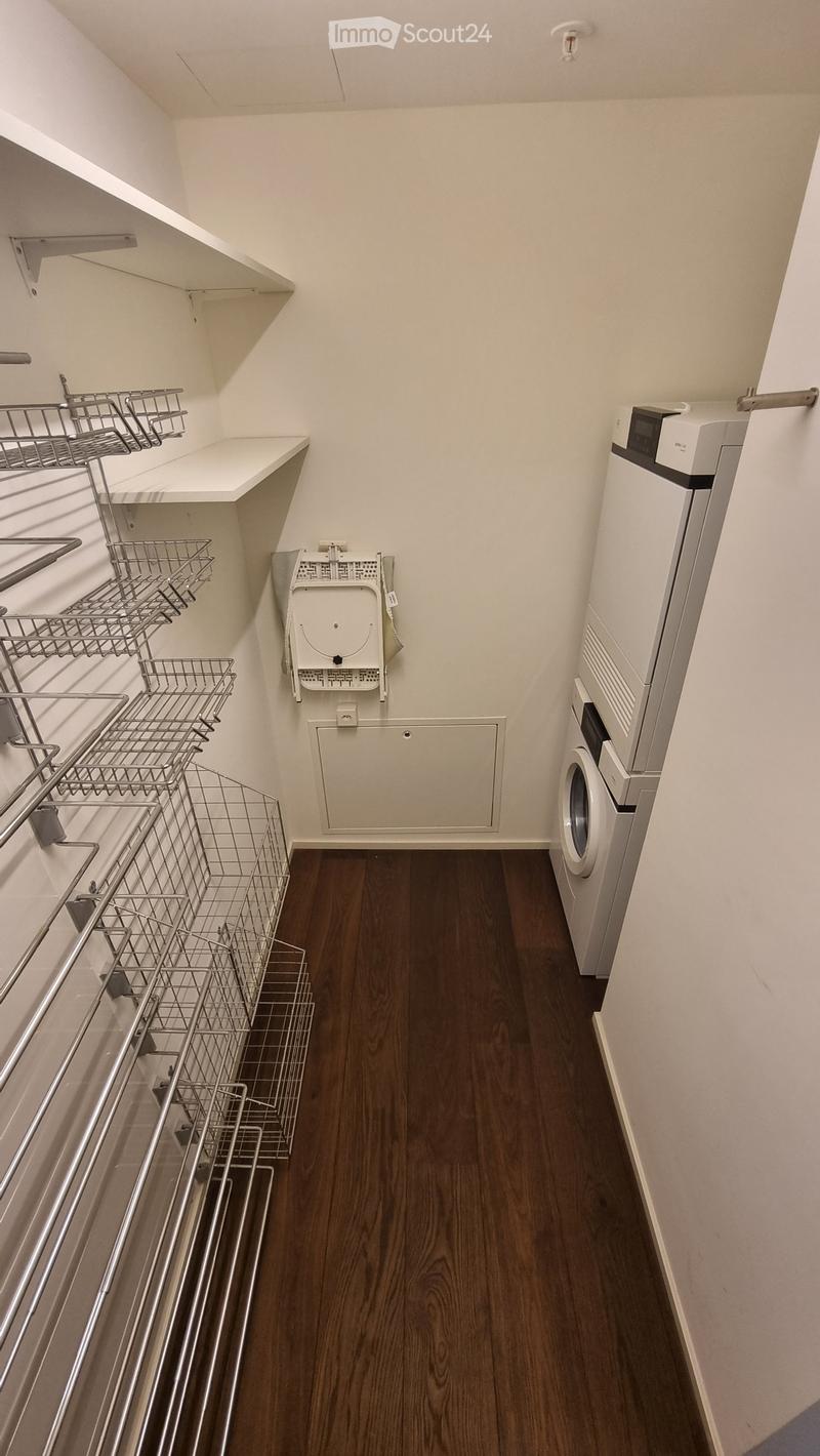 Laundry room with wooden floor, white walls, shelves, washing machine, and dryer