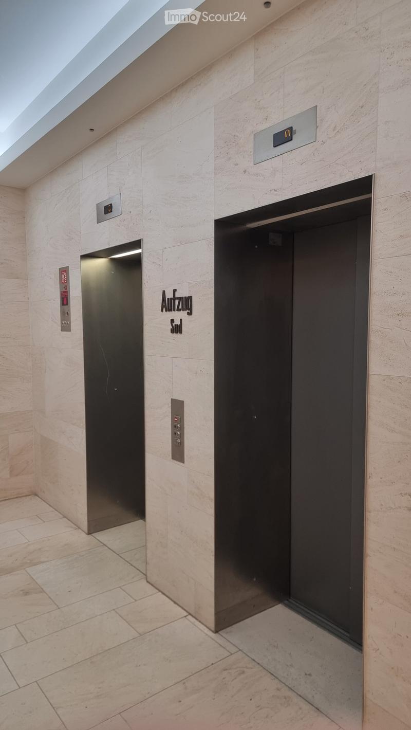 Two elevators, one labeled 'Aufzug' and the other 'Sud', both with digital displays and control panels, marble walls and floor.