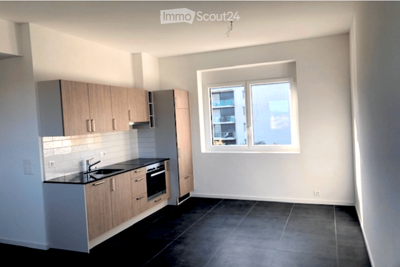 Modern kitchen with light wood cabinets, black countertops, and a large window overlooking a cityscape.