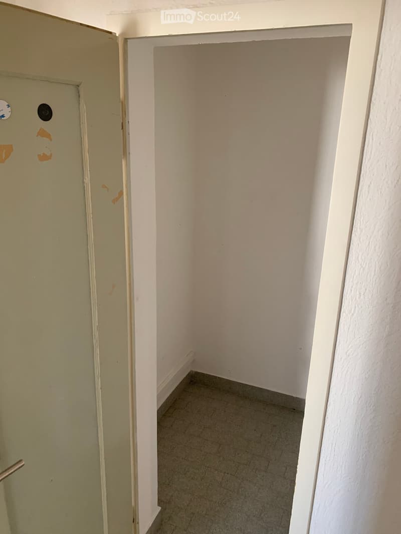 empty room with closed door, tiled floor, white walls, and a few small stains