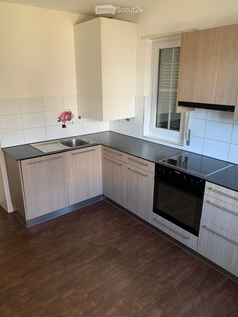 modern kitchen with black countertop, stainless steel sink, gas stove, wooden cabinets, white tiles