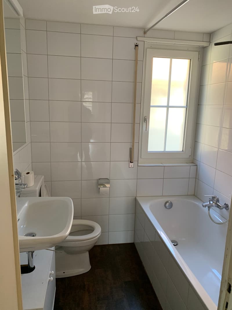white tiles, white bathtub, white toilet, white sink, mirror, toilet paper holder