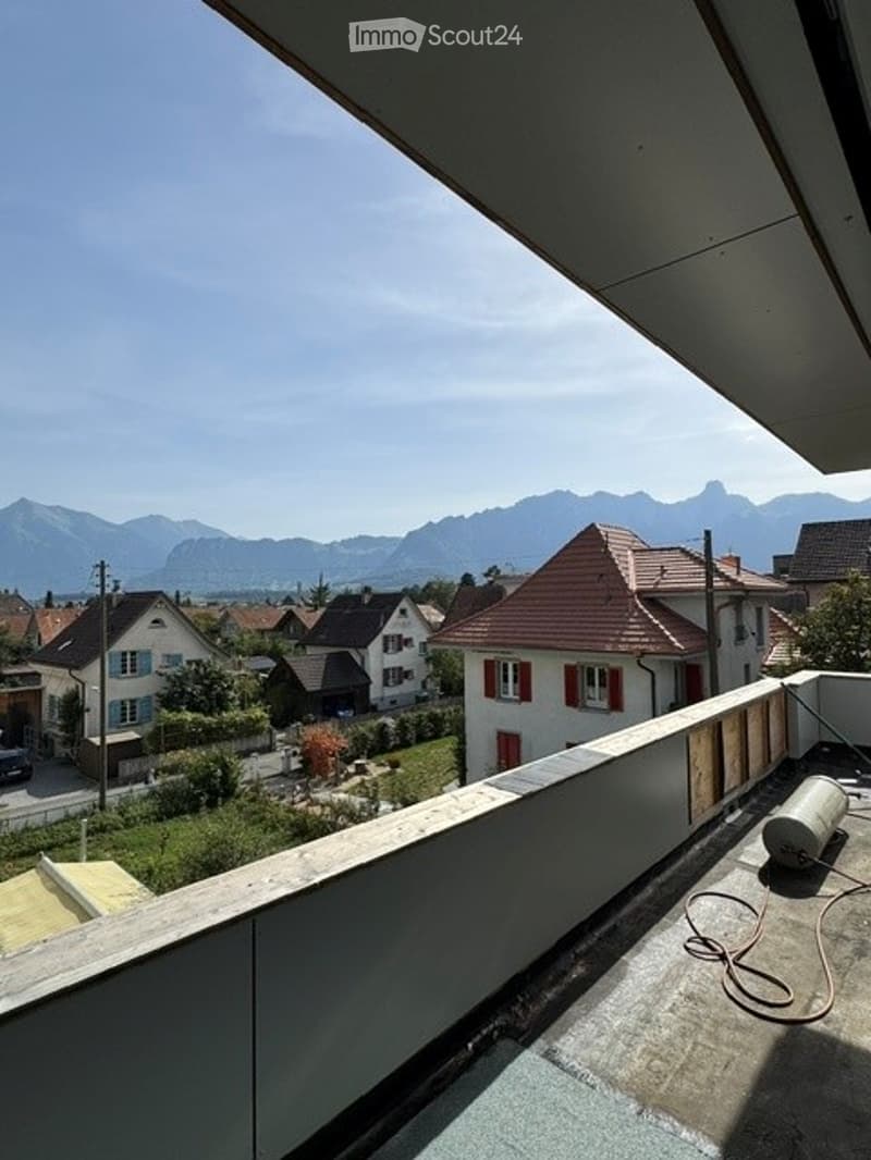 Balcony with a scenic mountain view, wooden railing, and some construction materials visible.