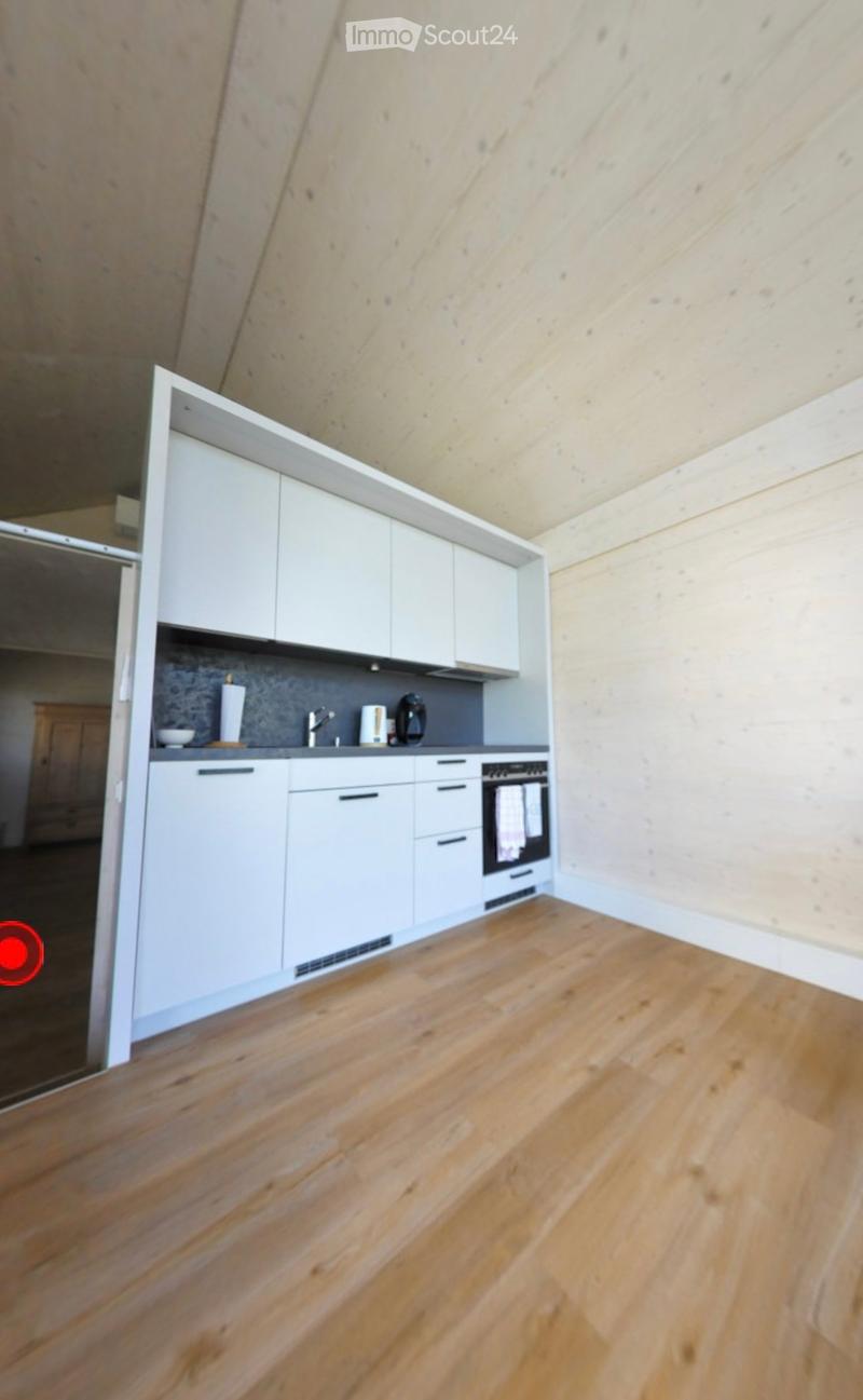 Modern kitchen with white cabinets, wooden flooring, and stainless steel appliances including a coffee maker and oven.