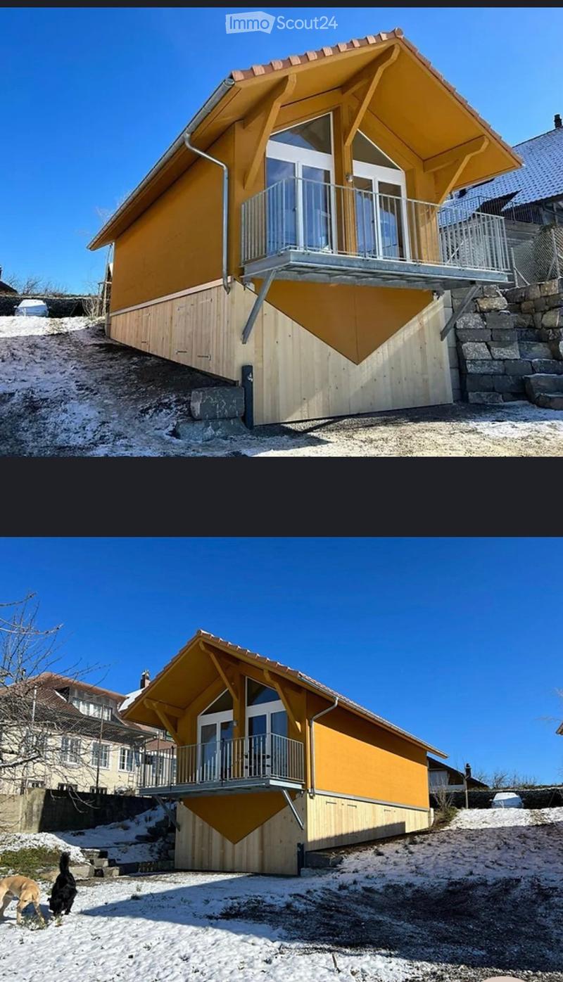 Modern two-story house with yellow exterior, large balcony, raised ground floor, and stone steps leading up to the entrance.