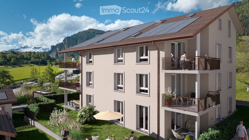 Multi-story residential building with balconies, solar panels on the roof, and scenic mountain view in the background.