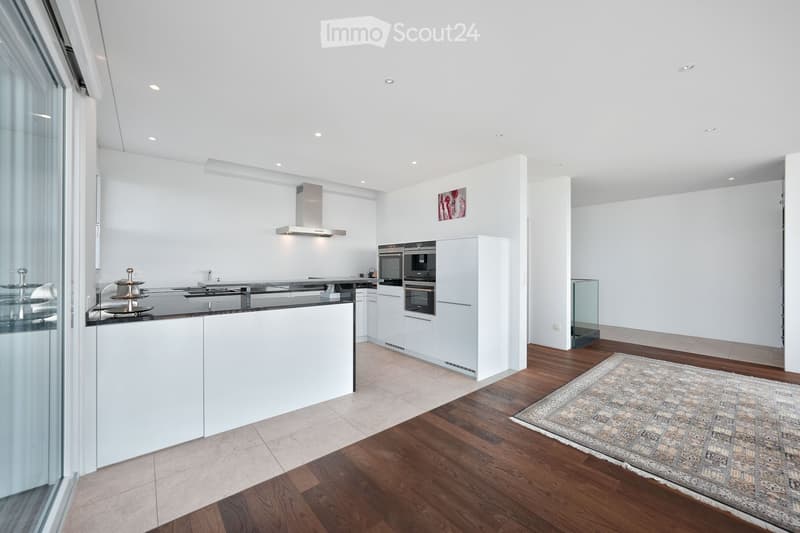 Modern kitchen with white cabinets, stainless steel appliances, island counter, and wooden flooring.
