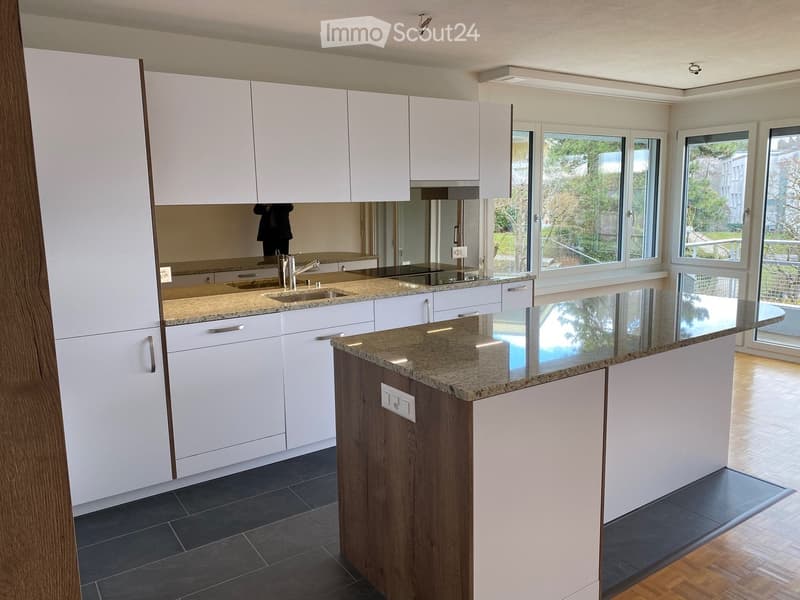 Modern kitchen with white cabinets, granite countertops, and a central island. Features a sink with a modern faucet and ample storage space.