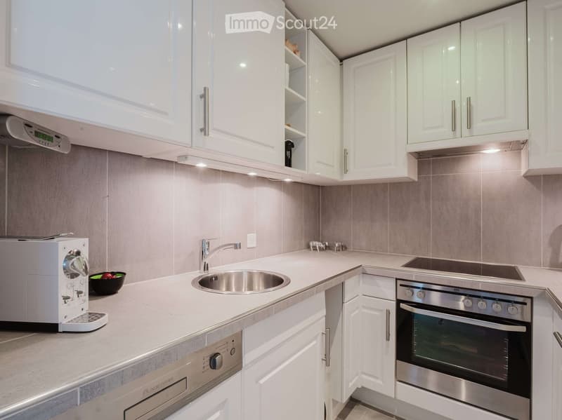 Modern kitchen with white cabinets, stainless steel appliances, and a light grey countertop.