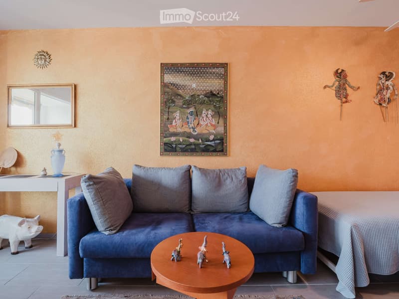 A cozy living room with a blue sofa, wooden coffee table, decorative items, and artwork on the walls.