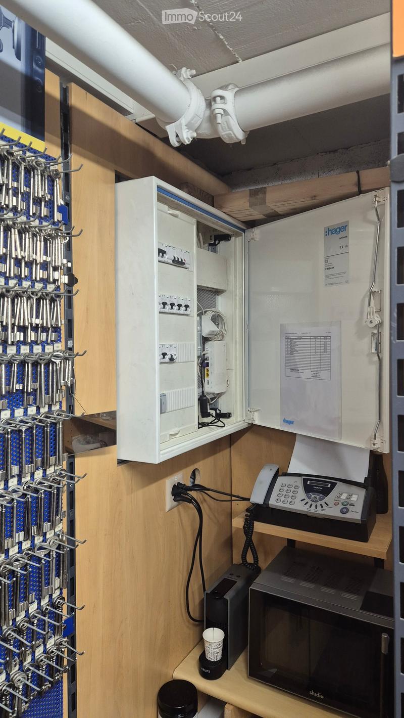 A small utility or break room with a microwave, telephone, and a cabinet with tools. The room features wooden walls and a white electrical panel.