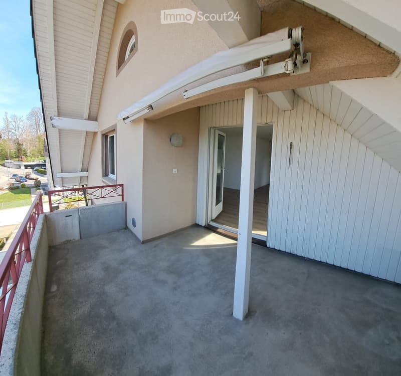 Balcony with concrete floor, white wooden railings, and access to a building entrance.