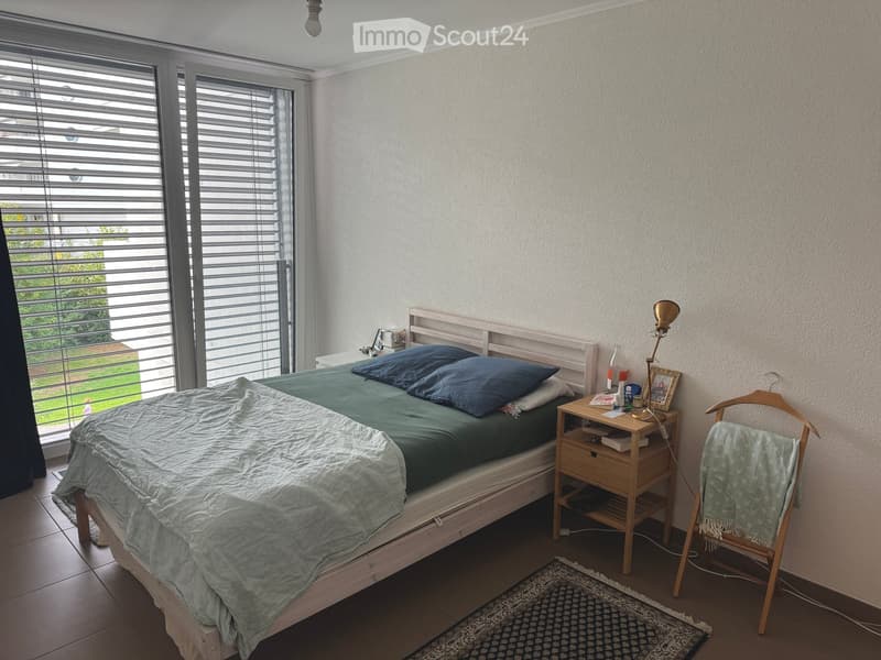 A modern bedroom with a wooden bed, nightstand, lamp, picture frame, and a small rug on the floor.