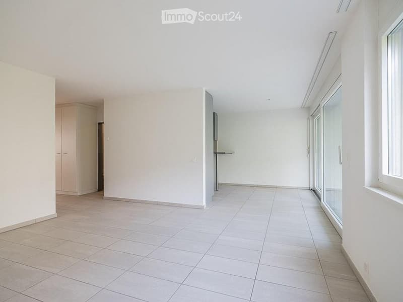 Empty room with white walls, tiled floor, and large windows. No furniture or equipment present.