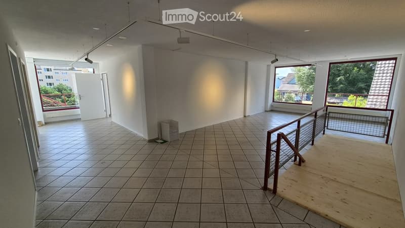 Empty room with tiled floor, white walls, large windows, and a balcony area with metal railings.