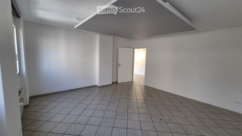 Empty room with tiled floor, white walls, and a single door leading to another space.