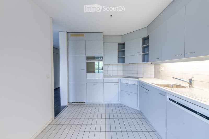 Modern kitchen with light blue cabinets, white tiled walls, and a white tiled floor. Features include a sink with a modern faucet, an oven, and a dishwasher.