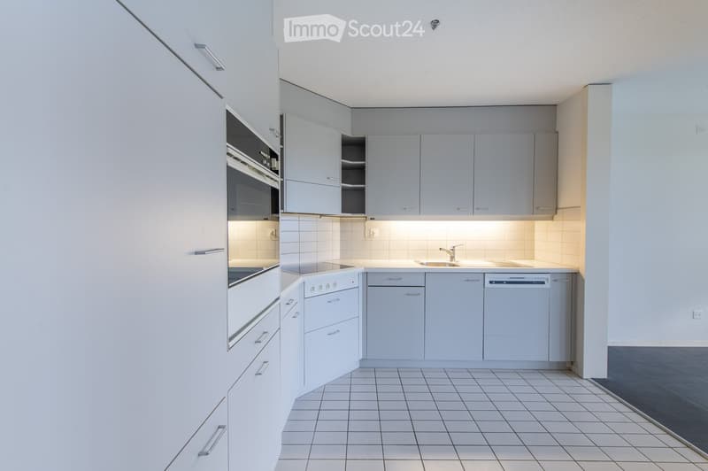 Modern kitchen with white cabinets, tiled floor, built-in oven, dishwasher, and sink.