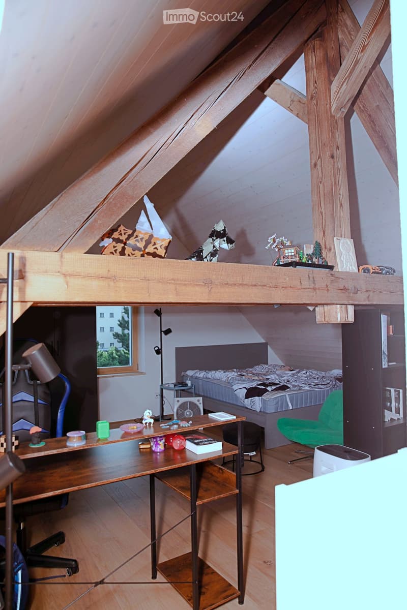 Cozy attic bedroom with wooden beams, slanted ceiling, and built-in loft bed. Features a desk, chair, lamp, fan, and decorative items.