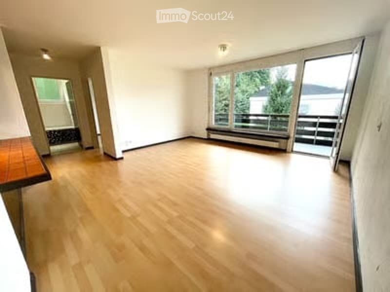Bright, empty room with wooden flooring, large windows, and a balcony view.