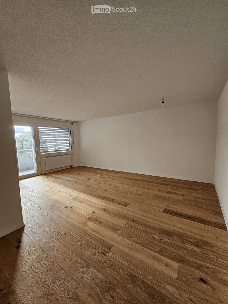 Empty room with wooden flooring, white walls, and a large window with blinds. No furniture or equipment is present.