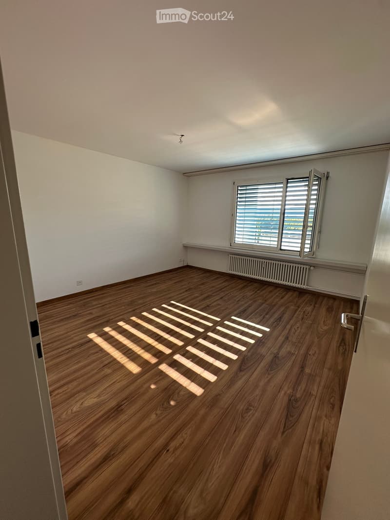 Empty room with wooden flooring, white walls, and a window with blinds. No furniture or equipment present.