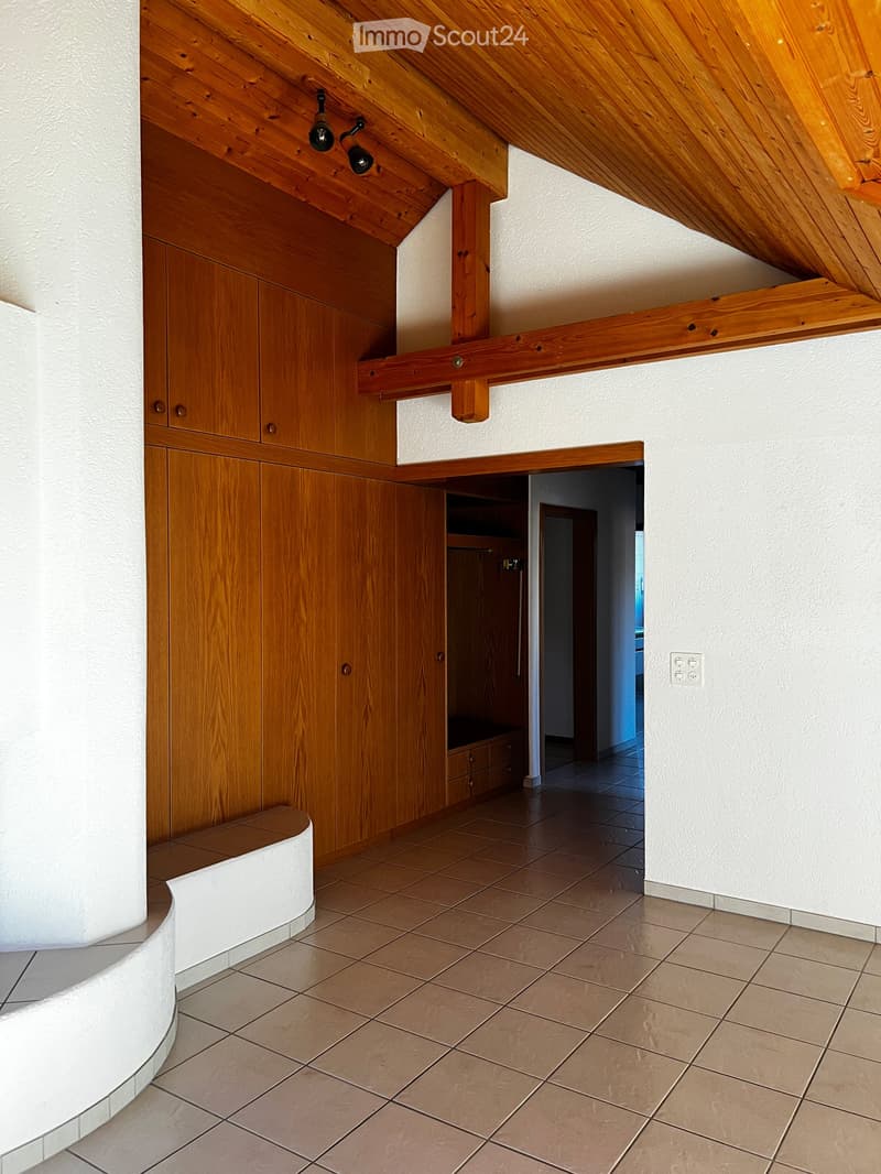 Hallway with wooden built-in cabinets, tiled floor, and exposed wooden beams on the ceiling. Features a built-in bench and recessed lighting fixtures.