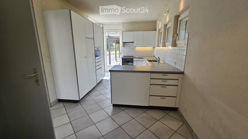 Modern kitchen with white cabinets, tiled floor, and built-in appliances including a stove, oven, and sink.