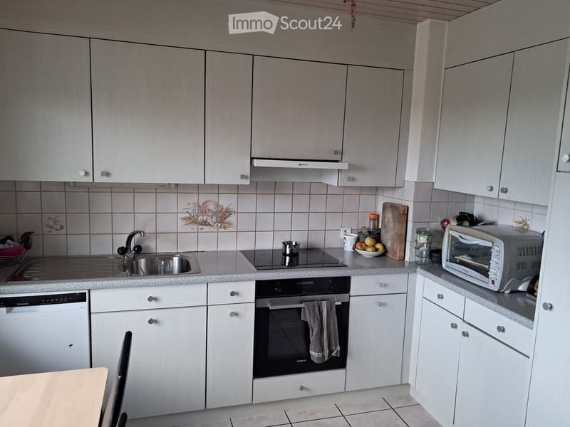 Modern kitchen with white cabinets, stainless steel appliances, and a granite countertop. Includes a sink, oven, dishwasher, toaster, and various kitchen items.