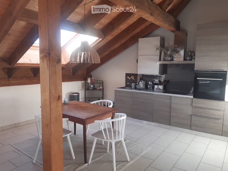 Modern kitchen with grey cabinets, white tiled floor, wooden dining table with white chairs, and various appliances including an oven, fridge, and sink.