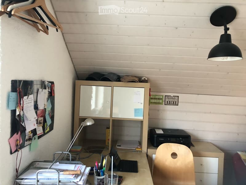A well-organized home office with a wooden desk, laptop, chair, lamp, cabinet, printer, and various office supplies.