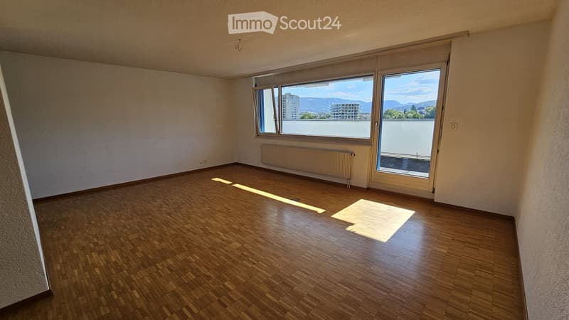 Empty room with wooden flooring, large windows, and a radiator. No furniture or equipment present.