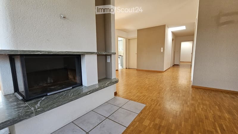 Empty hallway with wooden flooring, white walls, and a fireplace on the left side.